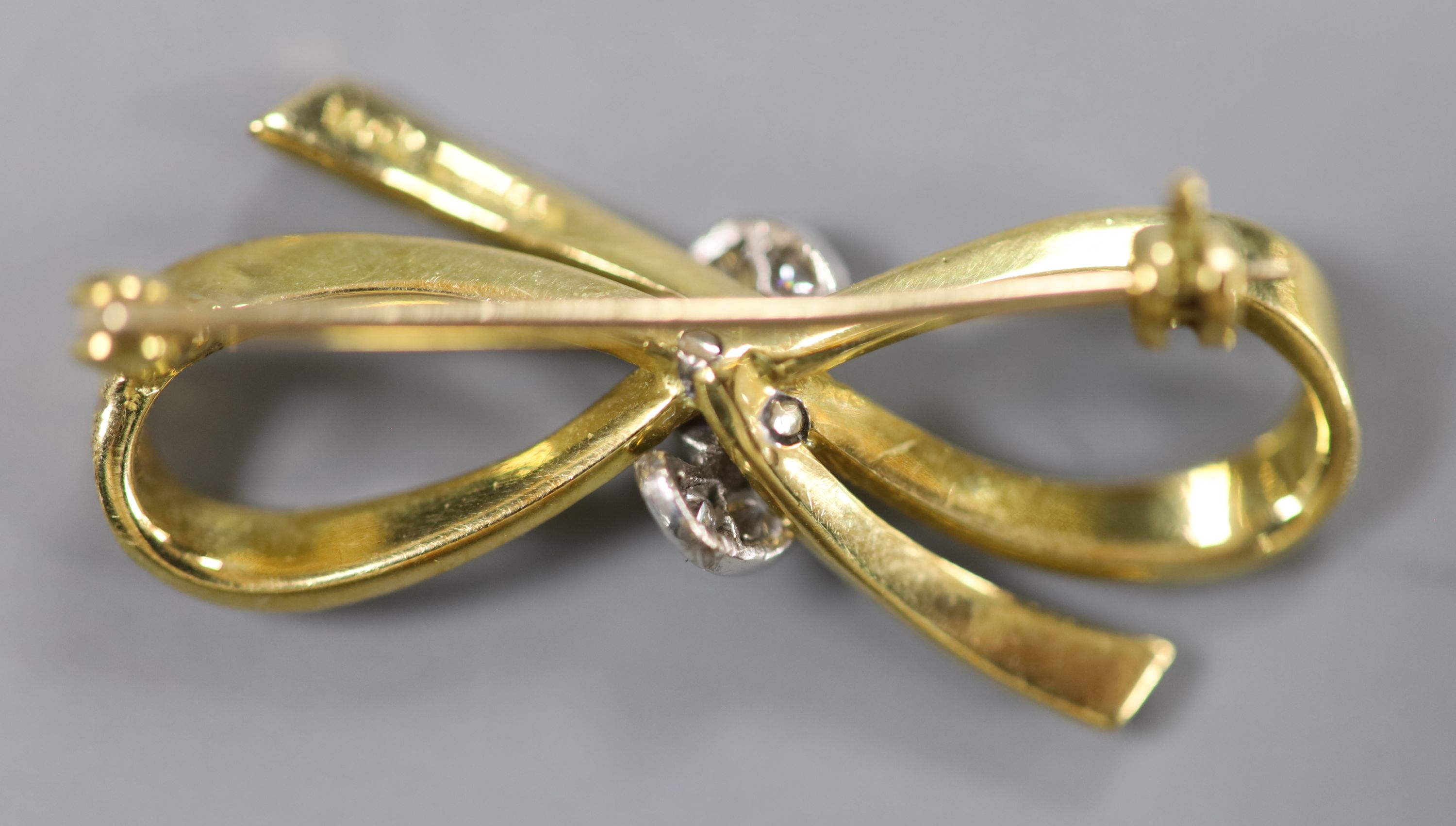 An 18ct gold and diamond bow brooch, 33mm, gross 5.4 grams.